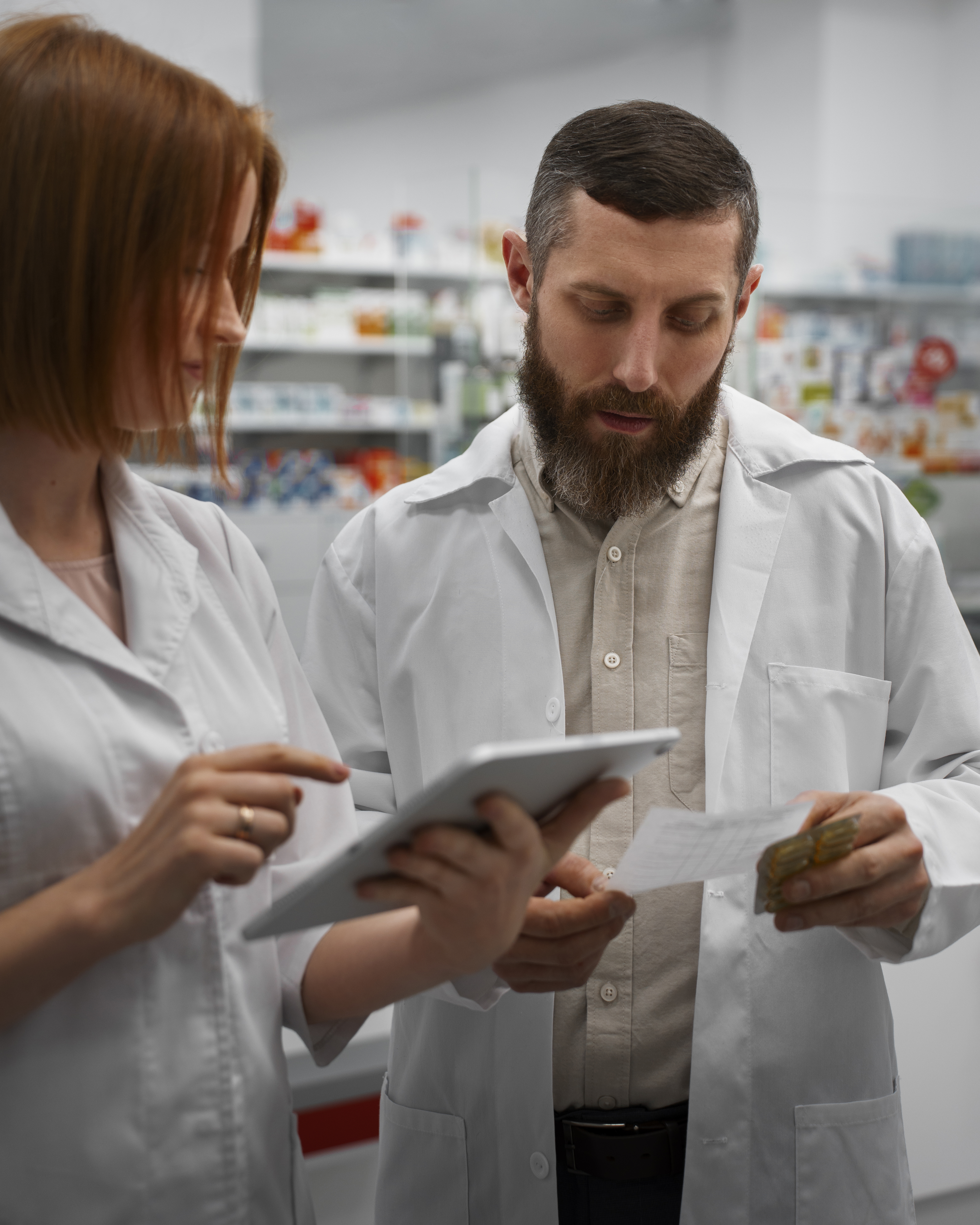 female-pharmacist-training-male-coworker-with-tablet-pharmacy (1)